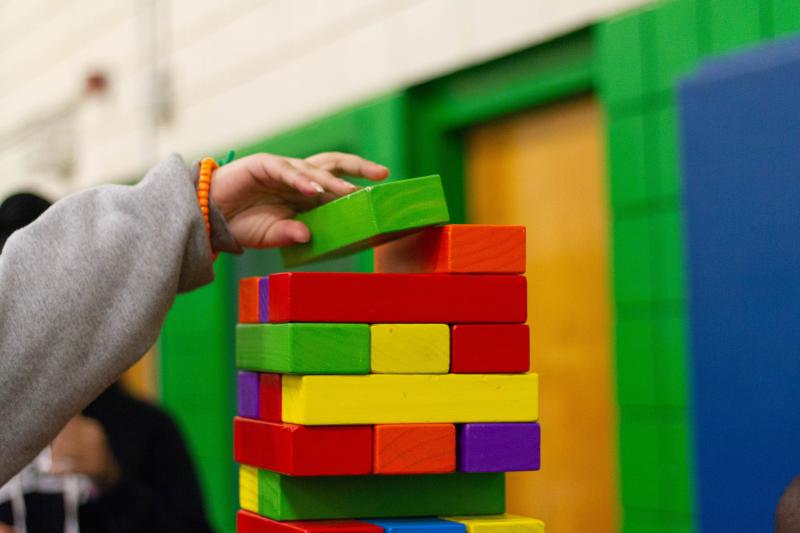 Child's handing setting colorful blocks in a stack. Photo by La-Rel Easter.